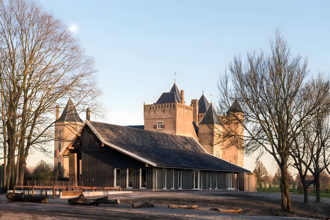 Bezoekerscentrum Slot Assumburg, Heemskerk: houten gebouw met zwarte gevel voor het kasteel